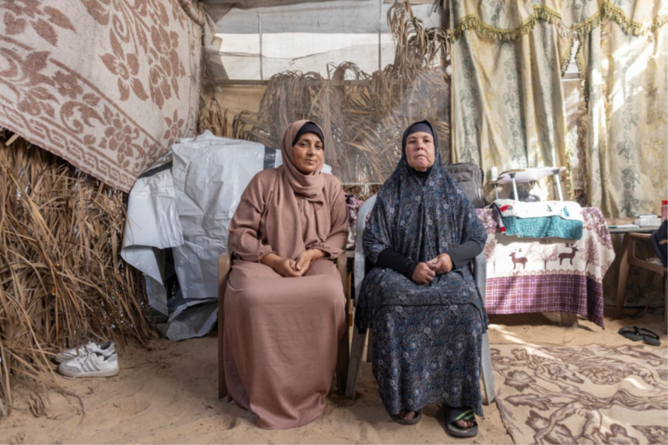 Farah (right) sits with her caregiver, Mona (left), in Al-Mawasi displacement area, Khan Younis, where they have been living since their home was destroyed during the war. Through the EU-funded Basic Needs Consortium, Farah receives multipurpose cash assistance to support their basic needs.